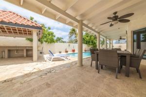 Un patio con mesa y sillas y una piscina. en Casa Luna Entire Home, en Palm-Eagle Beach