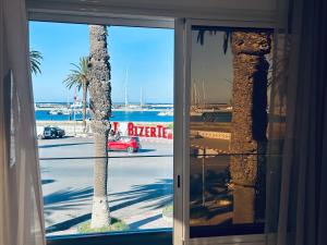 a window with a view of the ocean and a palm tree at BATUU Luxury Living in Bizerte