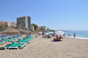 a beach with chairs and umbrellas and people on it at Apartamentos Mediterraneo in Marbella