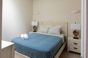 a white bedroom with a blue bed with two lamps at Dutch Caribbean Residence C in Palm-Eagle Beach