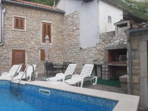 a group of white chairs and a swimming pool at House Dragica in Grižane