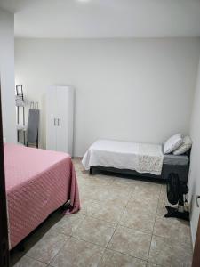a bedroom with two beds and a tiled floor at Residencial Carvalho Ap 4 in Torto