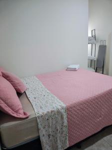 a bed with a pink comforter on top of it at Residencial Carvalho Ap 4 in Torto
