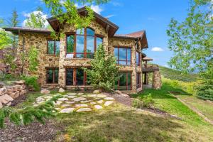 a stone house with large windows on a hill at Deer Valley Luxury Home in Gated Community, Private Hot Tub, Amazing Views, Gourmet Kitchen in Heber City