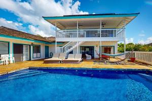 a villa with a swimming pool and a house at Makena in Koloa
