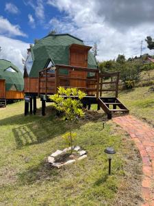 a wooden house with a green roof in a yard at Glamping Brillo de Luna in Guatavita