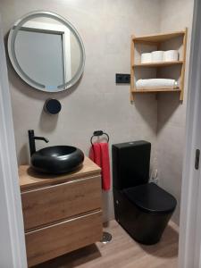 ein Bad mit einem schwarzen WC und einem Spiegel in der Unterkunft El Paseo a Madrid 169 - Junto a la Casa de Campo in Madrid