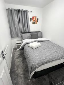 ein Schlafzimmer mit einem Bett mit einer grauen Bettdecke in der Unterkunft New Manchester City Getaway House with 2 FREE Parking in Manchester
