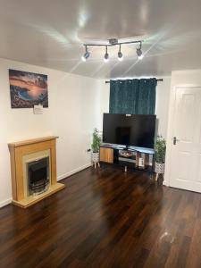 ein Wohnzimmer mit einem Flachbild-TV und einem Kamin in der Unterkunft New Manchester City Getaway House with 2 FREE Parking in Manchester