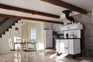 una cocina con electrodomésticos blancos, mesa y sillas en Maison Du Vieux Chemin, en Saint-Philémon