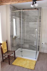 a shower with a glass door next to a chair at Maison Du Vieux Chemin in Saint-Philémon