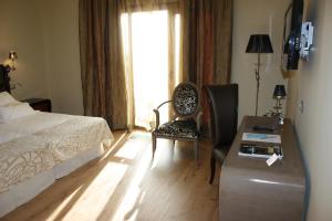 1 dormitorio con cama, escritorio y ventana en Hotel Spa Villa Nazules, en Chueca