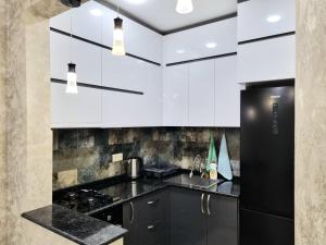 a kitchen with white cabinets and a black refrigerator at Sea apartment baTumi in Batumi