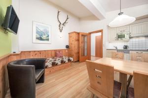 a kitchen and dining room with a dining table and a room with a bed at Apartments Alpina in Mayrhofen