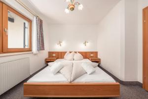 a bedroom with a bed with white sheets and pillows at Apartments Alpina in Mayrhofen