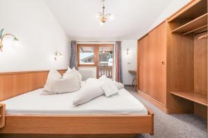 a bedroom with a bed with white sheets and pillows at Apartments Alpina in Mayrhofen +14 photos