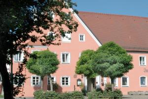 ノイブルク・アン・デア・ドナウにあるRomantik Hotel Zum Klosterbräuの木々が目の前に立つピンクの建物