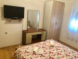 Schlafzimmer mit einem Bett, einem TV und einem Spiegel in der Unterkunft Apartments Kate in Zaton