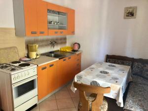 eine Küche mit Orangenschränken, einem Tisch und einem Herd in der Unterkunft Apartments Kate in Zaton