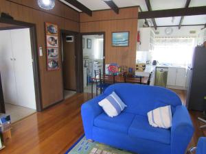 a living room with a blue couch and a kitchen at Honeysuckle Lodge in Cowes