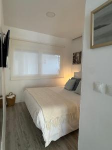 a white bedroom with a bed and a window at Cabopino Beach & Marina Apartment in Marbella +18 photos