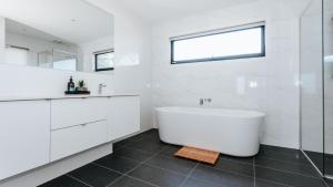 a white bathroom with a tub and a window at Tranquil Shores in Flinders +27 photos