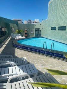 une piscine avec des chaises longues et un bâtiment dans l'établissement Sua casa na Ponta Verde 200m da praia, à Maceió