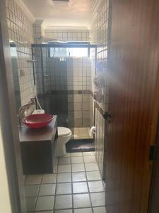 La salle de bains est pourvue d'un lavabo rouge et de toilettes. dans l'établissement Sua casa na Ponta Verde 200m da praia, à Maceió