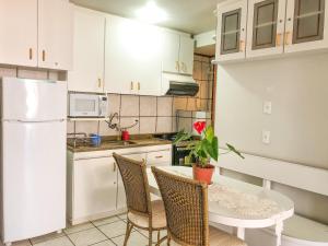 a kitchen with a table and a white refrigerator at Jurerê Internacional - Apartamento no Open Shopping in Florianópolis
