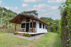 a small white house with a wooden roof at Acogedora cabaña Playa Hermosa Naturaleza y Surf in Playa Hermosa