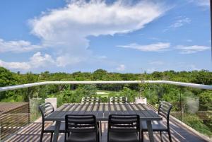 eine Terrasse mit Tisch und Stühlen auf einem Deck in der Unterkunft Penthouse with Beach Acces and Golf course in Akumal
