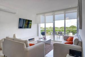 ein Wohnzimmer mit zwei Sofas und einem Fernseher in der Unterkunft Penthouse with Beach Acces and Golf course in Akumal