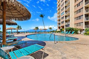 Una piscina con sillas y sombrillas en un resort. en Royal Kahana 1015, en Kahana
