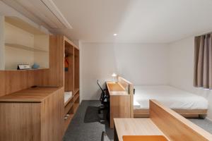 a small bedroom with a bed and a desk at Mangrove Jeju City in Jeju
