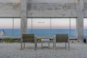 two chairs and a table with a view of the ocean at Mangrove Jeju City in Jeju