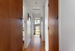 a hallway with white walls and wooden doors at Downtown Cosy Cottage in Mount Maunganui