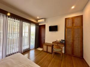 une chambre avec un lit, un bureau et une télévision dans l'établissement Luana Villa Ubud, à Ubud