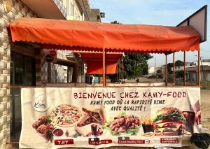 a sign for a pizza stand in front of a building at Mini Studio de Luxe in Thiès