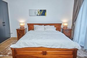 阿克拉iFORA Homes- Stylish 3 Bedroom Condo near A&C Mall的一间卧室配有一张带2个床头柜的大型木床 更多6张照片
