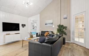 Una sala de estar con un sofá de cuero negro y una mesa. en 9 Bedroom Awesome Home In Blåvand, en Blåvand