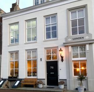 een wit gebouw met een zwarte deur en een bank bij Logeren aan de Haven - Appartement Spijkerbrug in Middelburg