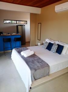 a bedroom with a large white bed with blue pillows at Chalé Jenipapo in Serra do Cipo