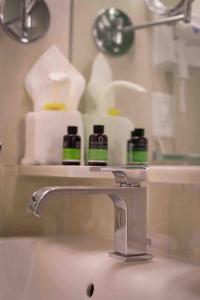 a bathroom sink with a faucet and some towels at Othelo Boutique Hotel Mexico in León +44 photos