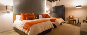 Habitación de hotel con 2 camas con almohadas de color naranja en Othelo Boutique Hotel Mexico en León