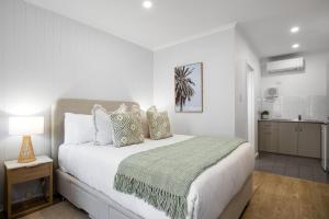 a white bedroom with a bed and a kitchen at Bayscape Studio Glenelg in Glenelg