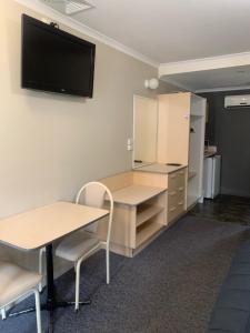 a room with a desk and a tv on the wall at Mid Coast Motor Inn in Macksville