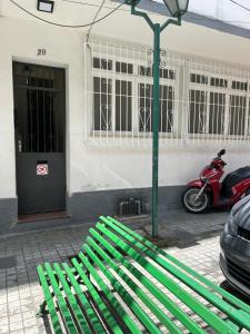 a green bench sitting in front of a building at Novíssimo apt 1 quarto Centro frente à Prefeitura in Nova Friburgo