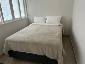 a bedroom with a bed with a blanket on it at Novíssimo apt 1 quarto Centro frente à Prefeitura in Nova Friburgo