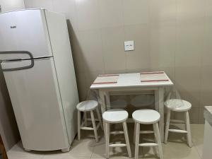 a kitchen with a counter with stools next to a refrigerator at Novíssimo apt 1 quarto Centro frente à Prefeitura in Nova Friburgo