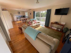 a living room with a couch and a table and a television at Relaxing Raglan & the Boat House in Raglan